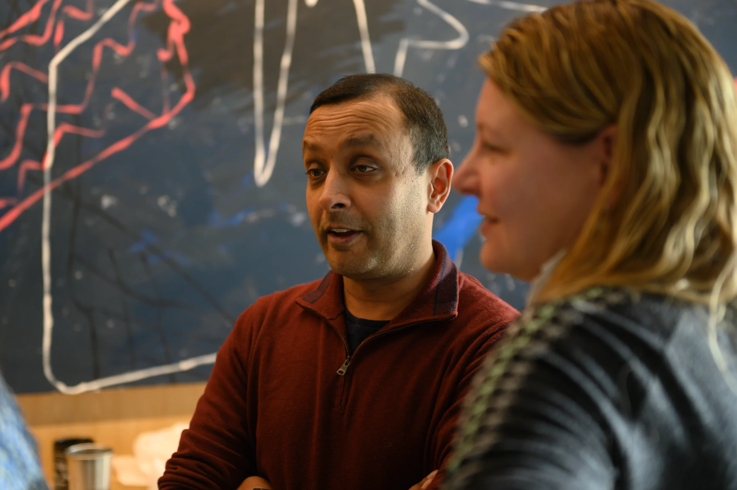 Engaged team conversation with a chalk board behind them