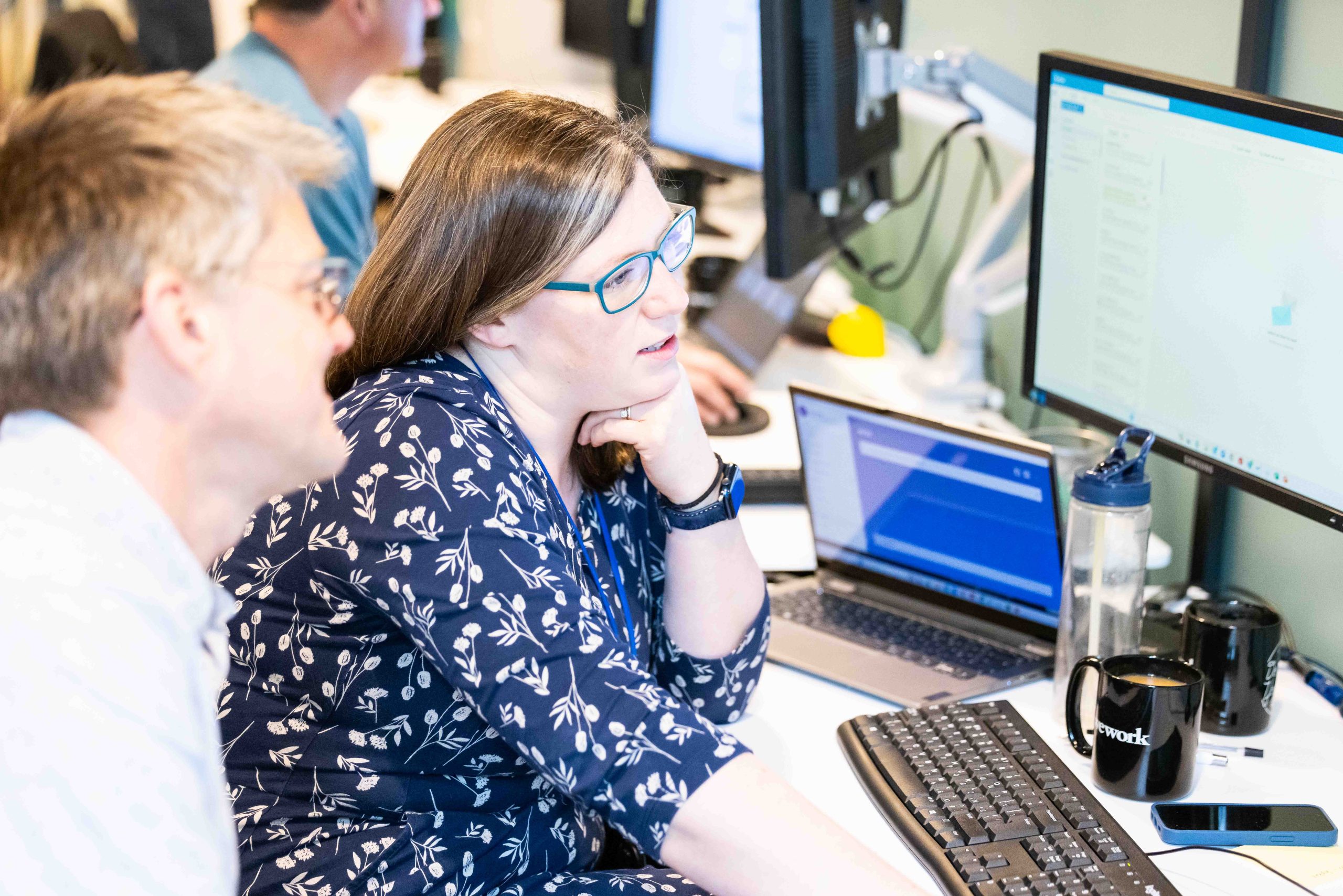 Two research scientists reviewing data on a laptop and screens
