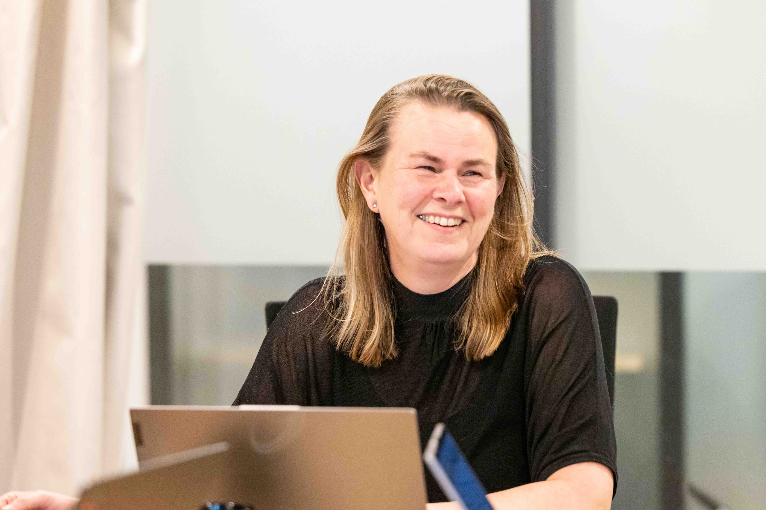 Happy smiling face of a person in a meeting with laptop open in front