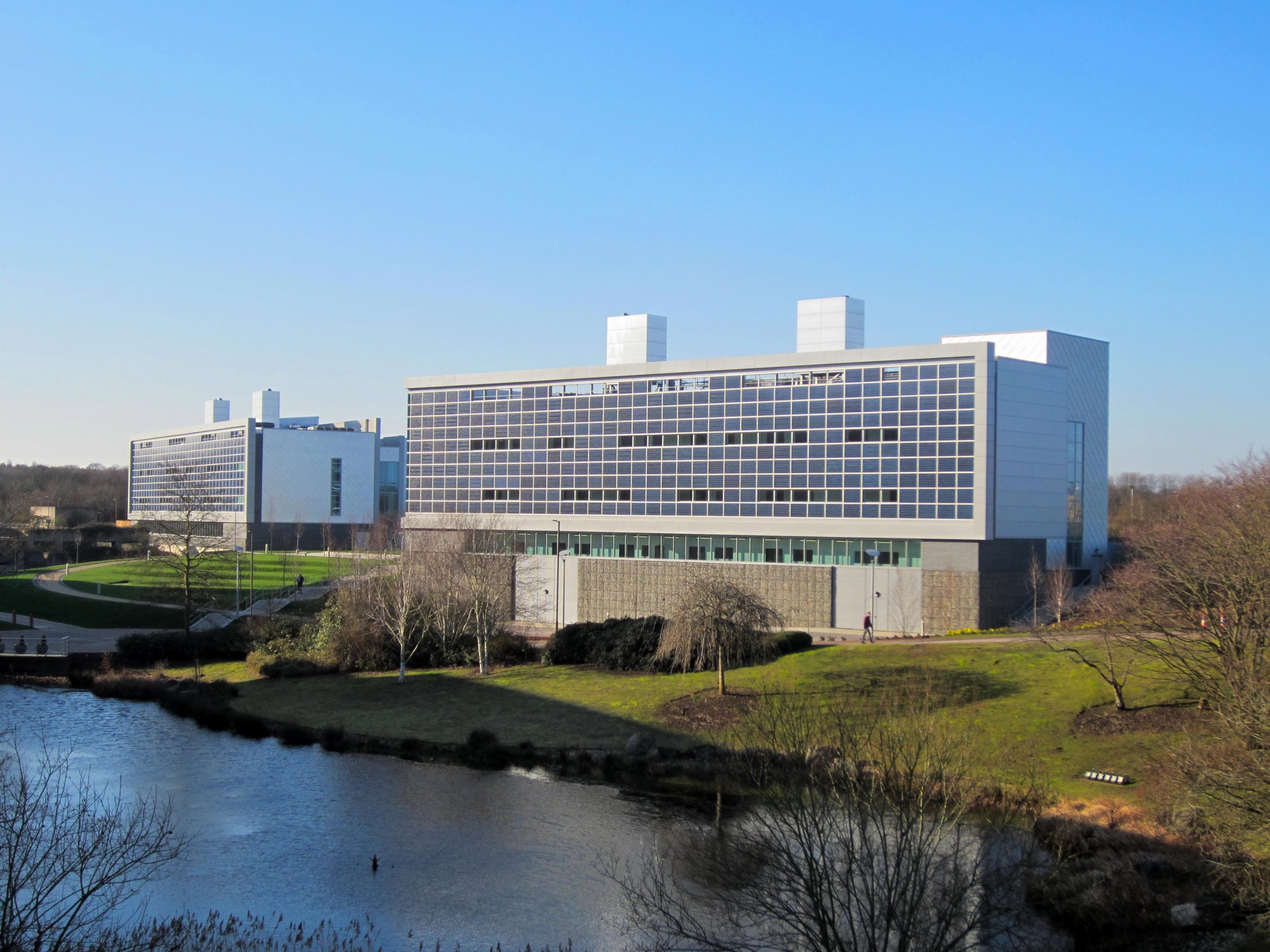 Research building behind a lake with lots of trees and grass